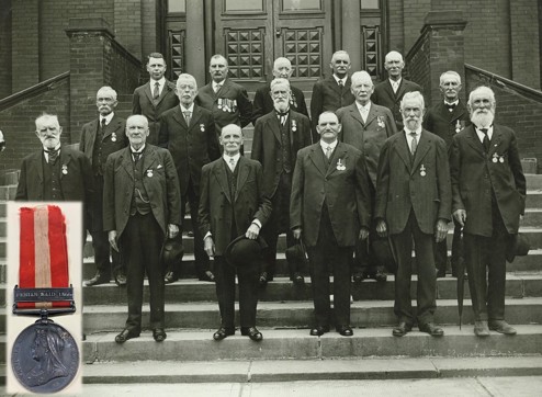Photograph of a group of veterans with a medal in the foreground.